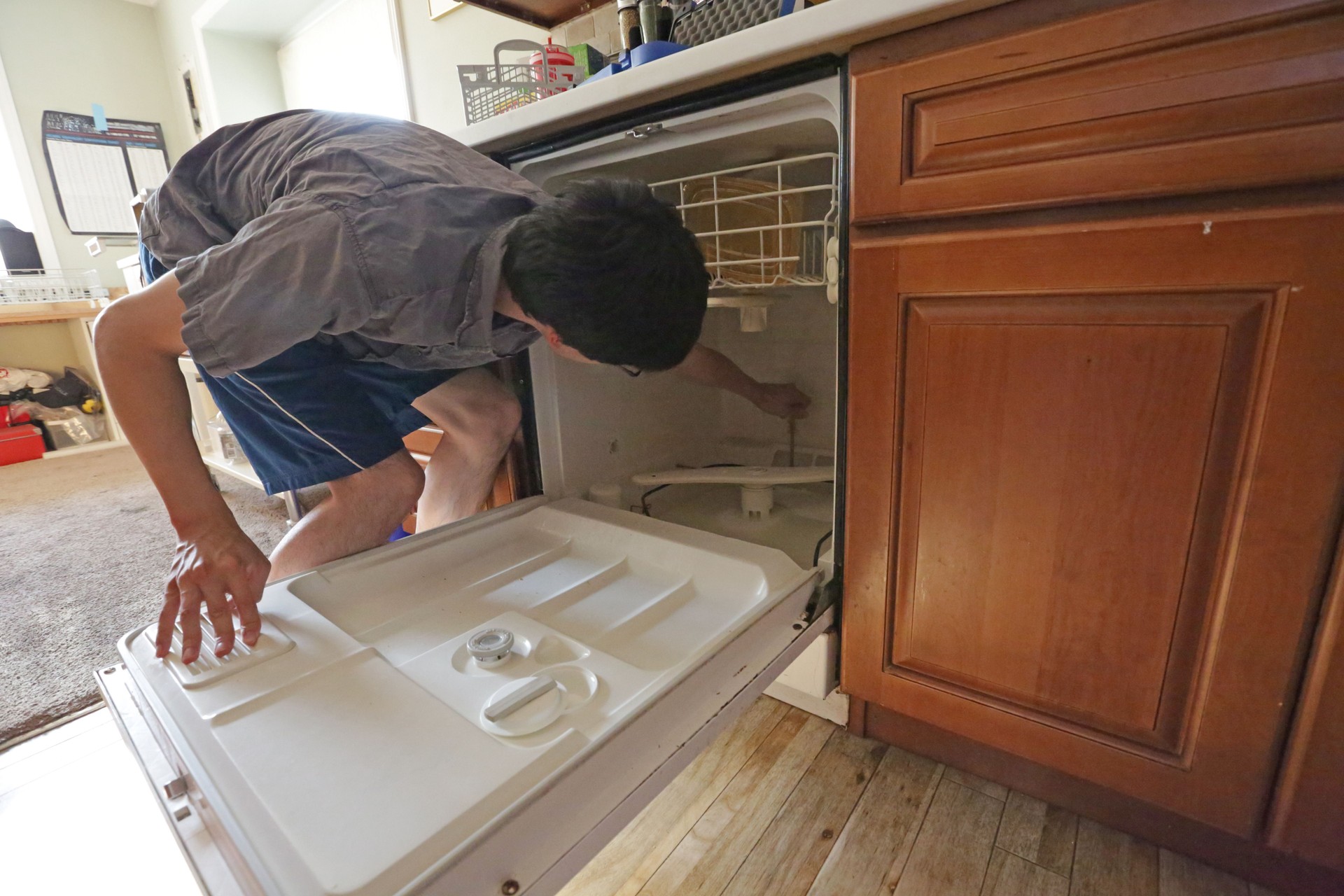 Young Man Repairs Dishwasher at Home