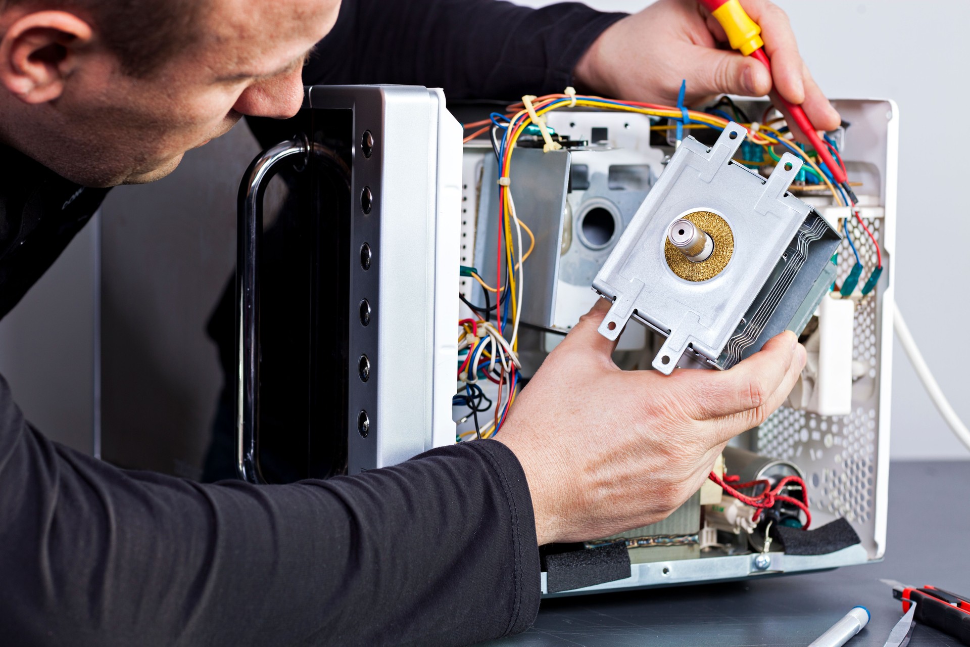 Serviceman electrician repairs a magnetron in the microwave